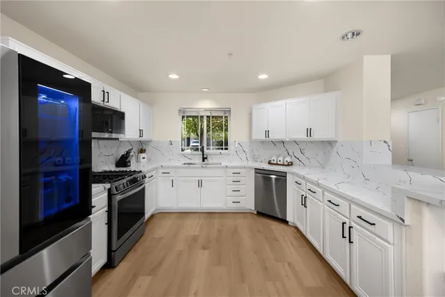 a kitchen with stainless steel appliances granite countertop a stove top oven a sink dishwasher a refrigerator and a oven with wooden floor