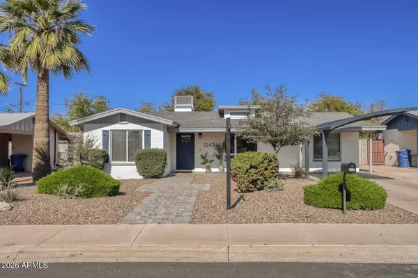 a front view of a house with a yard and potted plants