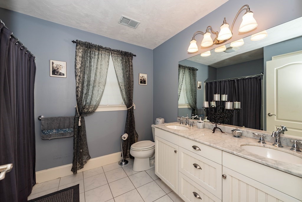 63 Bridge Street Raynham, MA 02767 - Photo 29 of 38 a bathroom with a double vanity sink toilet and shower