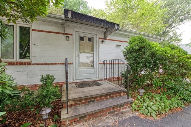 a view of a house with a small yard and a large tree