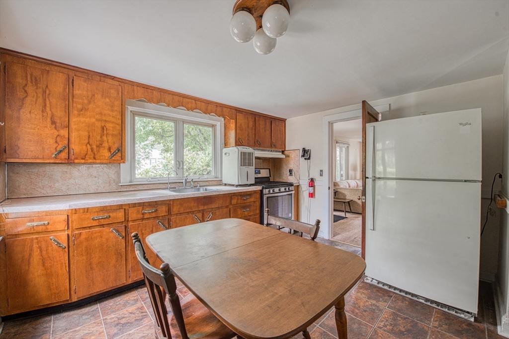 197 Turnpike Street Canton, MA 02021 - Photo 8 of 17 a kitchen with stainless steel appliances granite countertop a refrigerator a sink dishwasher a stove a dining table and chairs with wooden floor