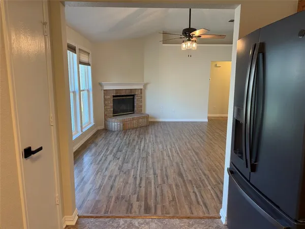 a view of a livingroom with a fireplace a ceiling fan and wooden floor