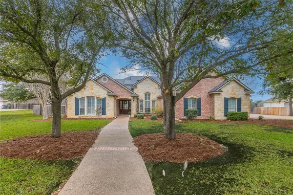 a front view of a house with a yard and trees