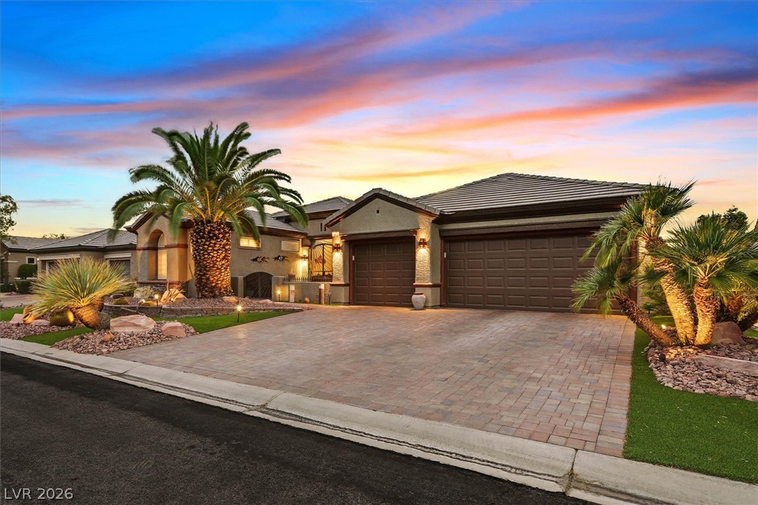 1823 Baton Rouge Street Henderson, NV 89052 - Photo 2 of 60 A spacious paved driveway leads to a modern three-car garage framed by manicured desert landscaping.