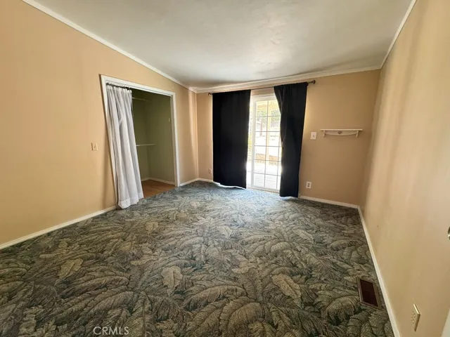 a view of an empty room with closet and a window
