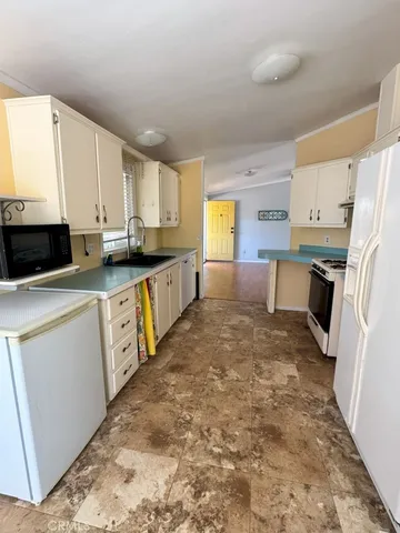 a large kitchen with kitchen island a sink a stove a refrigerator a white cabinets and wooden floor