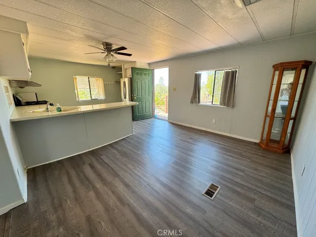 a kitchen with stainless steel appliances granite countertop a stove a sink and white cabinets with wooden floor