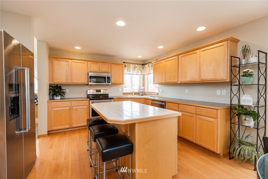 659 Shadow Avenue Northeast Renton, WA 98059 - Photo 7 of 37 a kitchen with stainless steel appliances granite countertop a stove a sink a refrigerator white cabinets and wooden floor