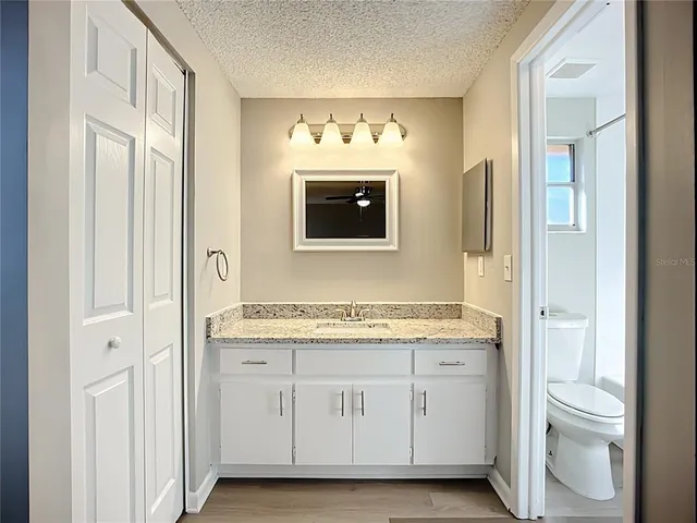 a bathroom with a granite countertop sink mirror and toilet