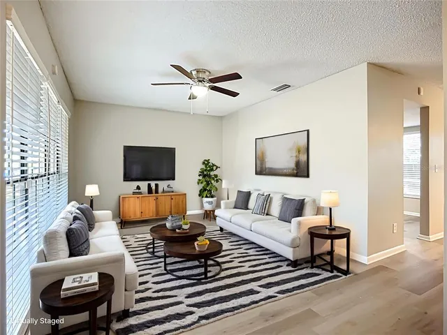 a living room with furniture a flat screen tv and a window