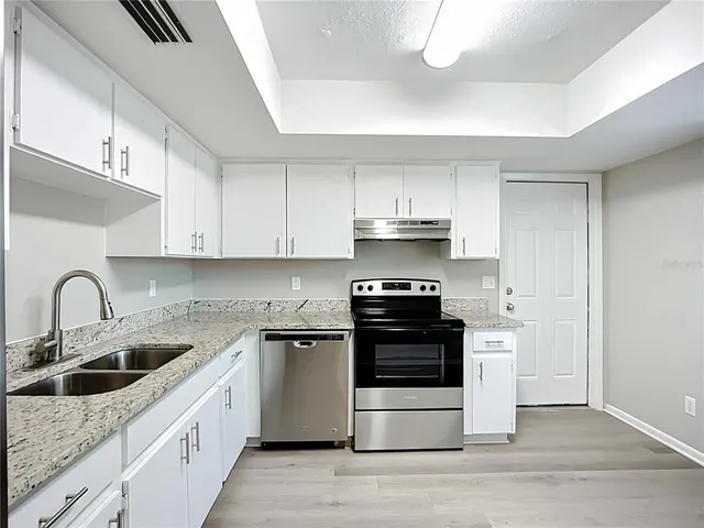 a kitchen with stainless steel appliances granite countertop a sink stove and refrigerator
