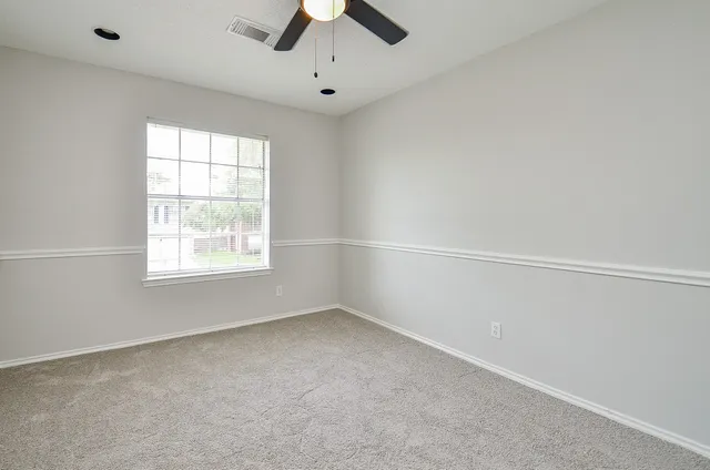 an empty room with a window and ceiling fan