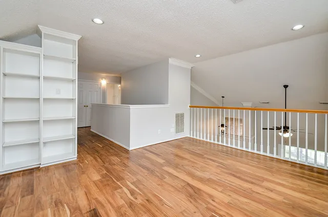 a view of an empty room with wooden floor and entryway