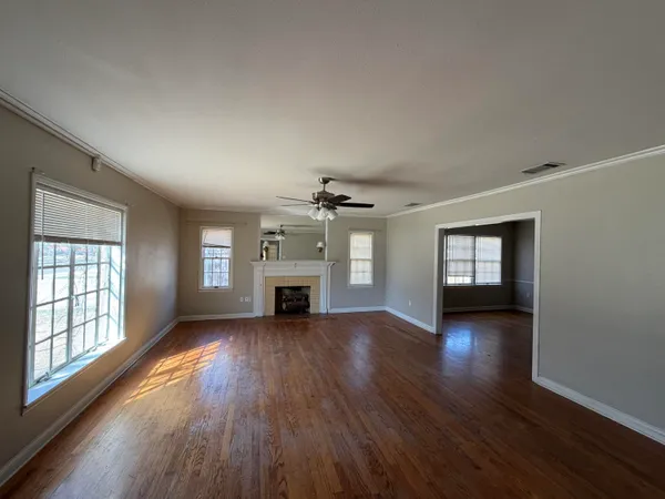 an empty room with windows fireplace and wooden floor