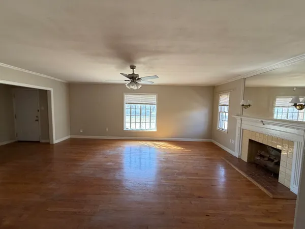 an empty room with windows fireplace and wooden floor