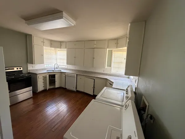 a kitchen with stainless steel appliances a sink a stove a refrigerator cabinets and a window