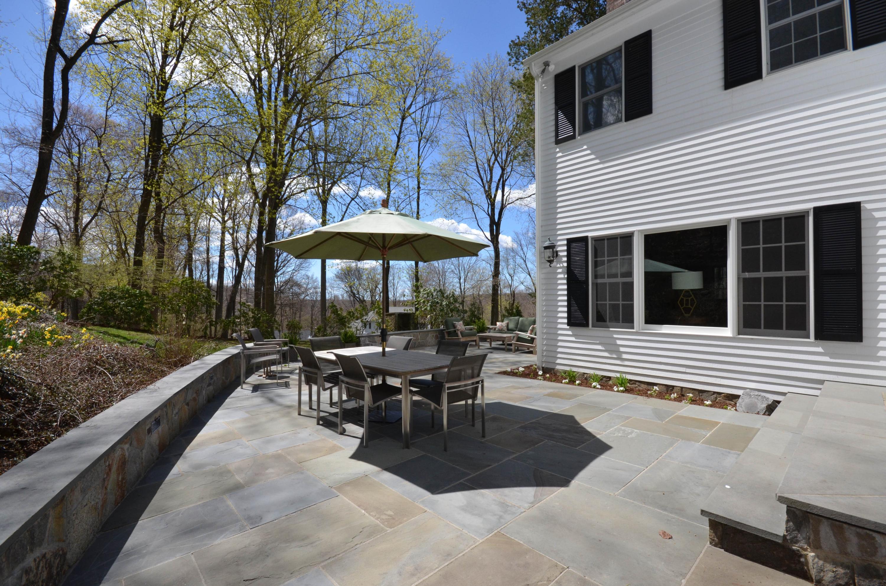 222 Marshall Ridge Road New Canaan, CT 06840 - Photo 42 of 49 a view of a patio with a table and chairs under an umbrella