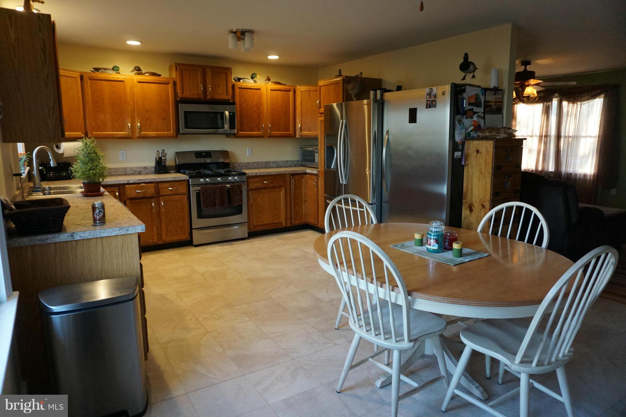 11629 Lynch Road Worton, MD 21678 - Photo 4 of 15 a kitchen with stainless steel appliances a refrigerator a stove a dining table and chairs