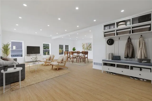 a living room with furniture kitchen view and a wooden floor