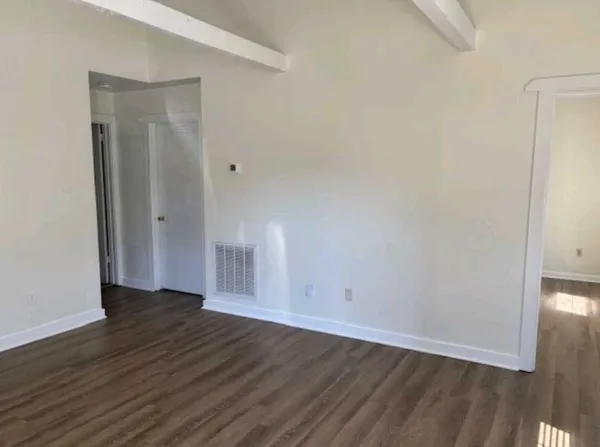 a view of an empty room with wooden floor and closet