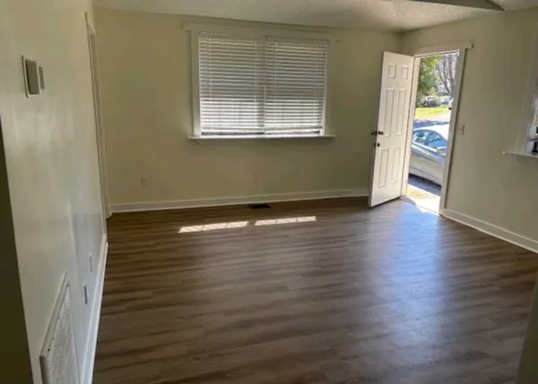 an empty room with wooden floor and windows