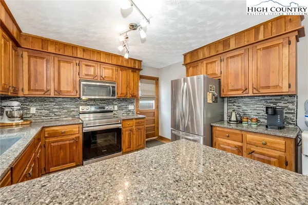 a kitchen with stainless steel appliances granite countertop a stove top oven a sink dishwasher a dining table and chairs with wooden floor