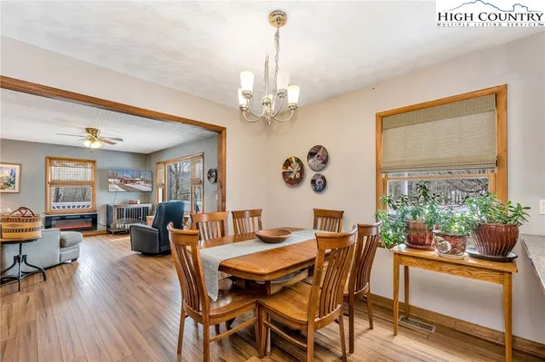 a dining room with wooden floor a chandelier a wooden table and chairs