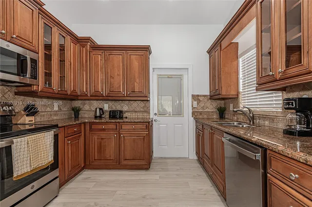 a kitchen with stainless steel appliances granite countertop a stove a sink dishwasher and a microwave oven with wooden cabinets