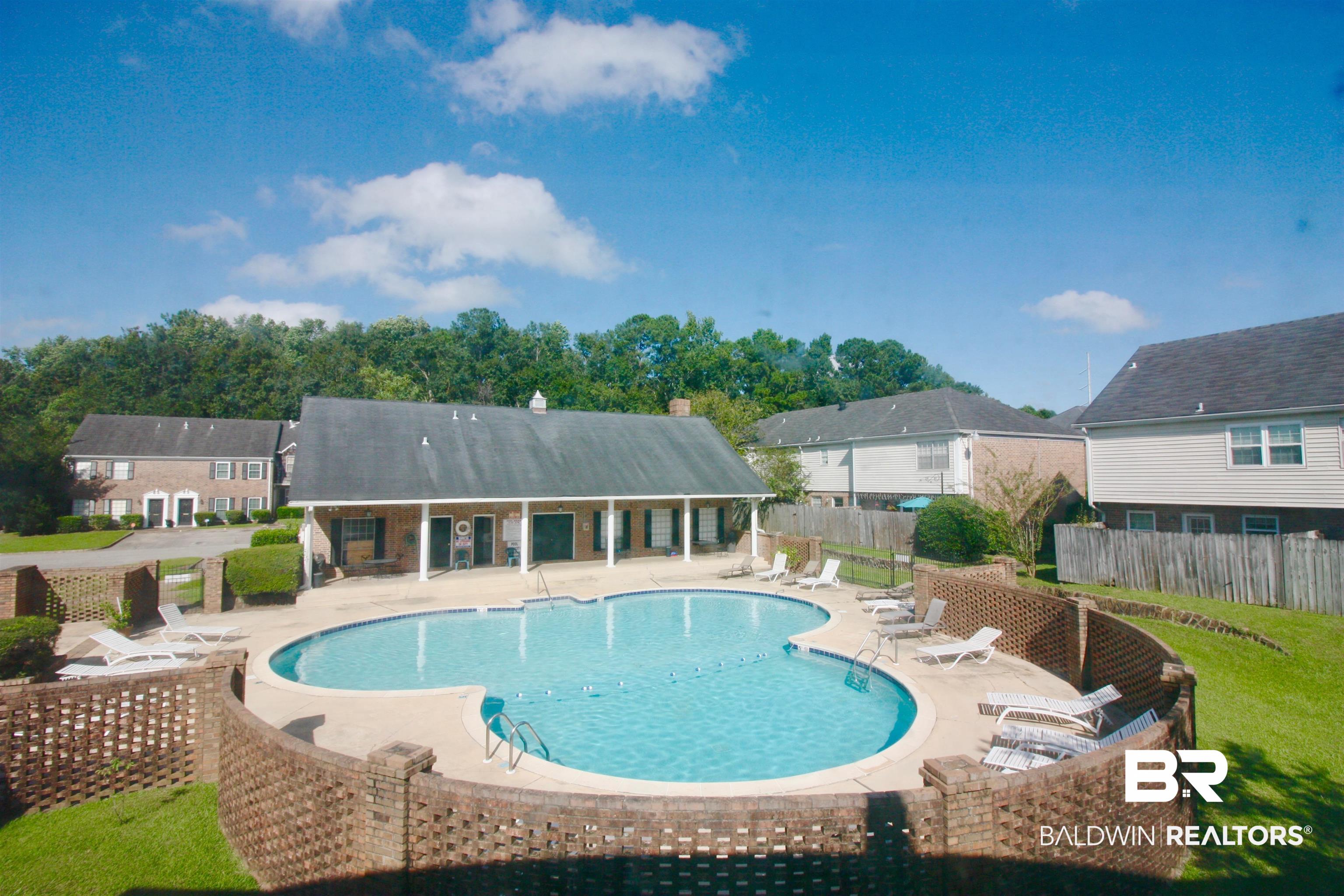 118 Du Rhu Drive, Unit H Mobile, AL 36608 - Photo 19 of 19 Freeform swimming pool with brick perimeter wall, surrounded by a clubhouse and residential structures