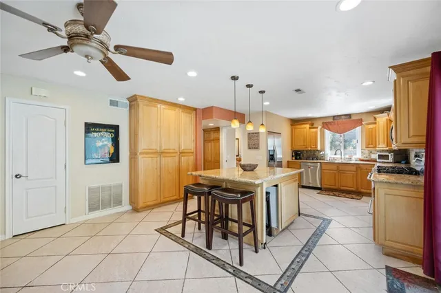 a kitchen with stainless steel appliances kitchen island granite countertop a table chairs sink and cabinets