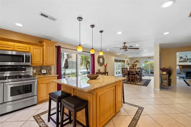 a kitchen with stainless steel appliances kitchen island granite countertop a stove a sink a dining table and chairs with the view of living room
