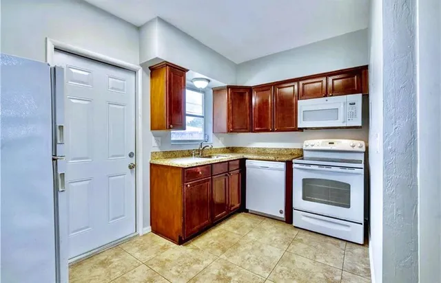 a kitchen with stainless steel appliances granite countertop a stove a sink and a refrigerator with wooden cabinets