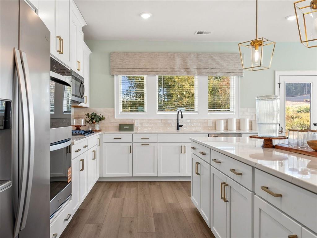 6410 Pinin Place Cumming, GA 30041 - Photo 3 of 11 a kitchen with granite countertop white cabinets white appliances a sink and a window