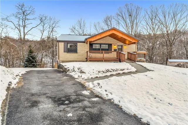 a front view of a house with a yard covered in snow