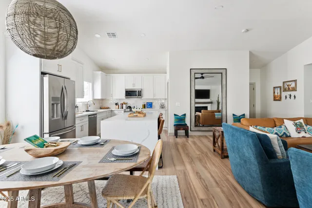 a living room with stainless steel appliances furniture a dining table and kitchen view