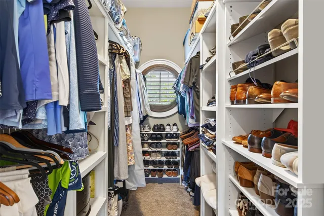 a view of walk in closet with clothes and shoes
