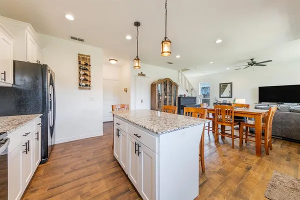a open kitchen with stainless steel appliances kitchen island granite countertop a table chairs and a refrigerator