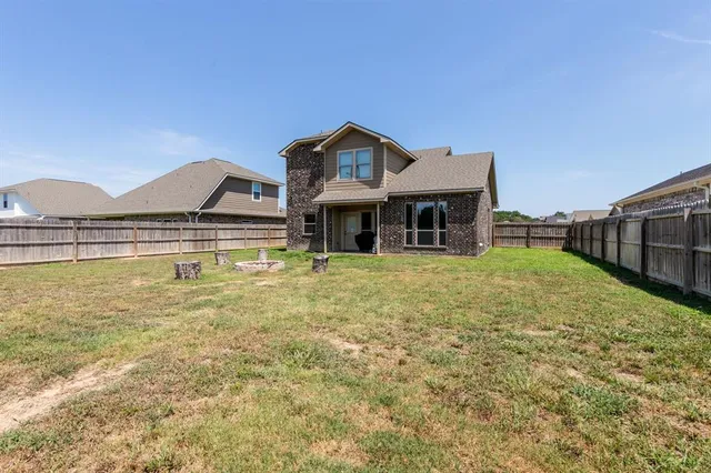 a front view of a house with a yard and a large tree