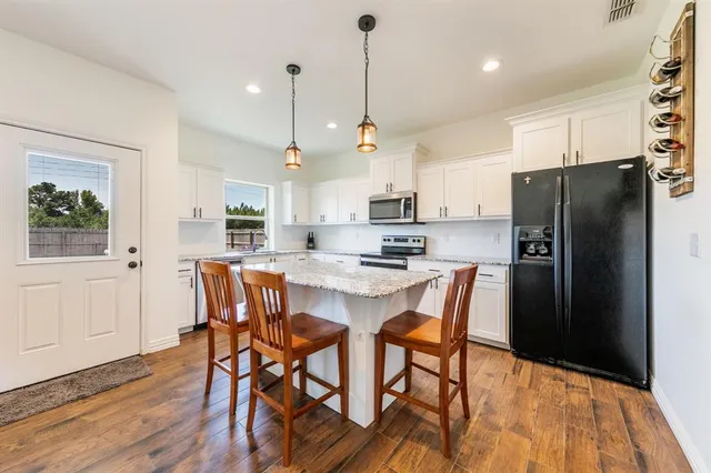 a kitchen with stainless steel appliances a dining table chairs refrigerator and microwave