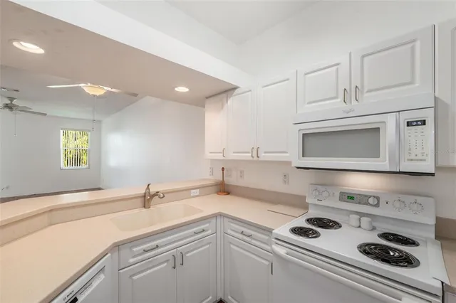 a view of kitchen and empty room with wooden floor
