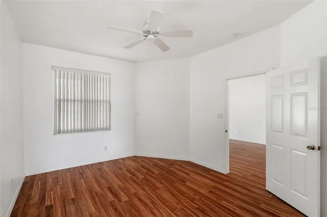 an empty room with a window and a ceiling fan