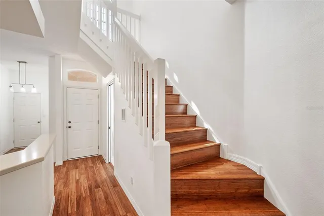 a room with stainless steel appliances kitchen island granite countertop a sink a stove and a refrigerator with wooden floor