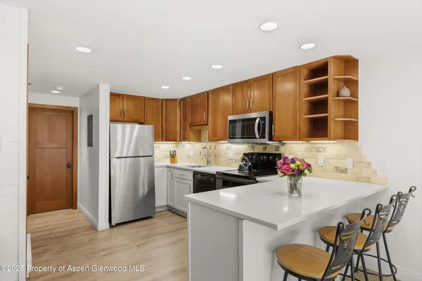 a kitchen with refrigerator and chairs