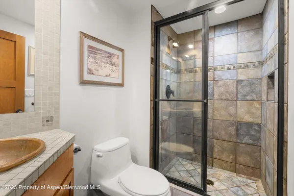 a bathroom with a granite countertop toilet a sink and shower
