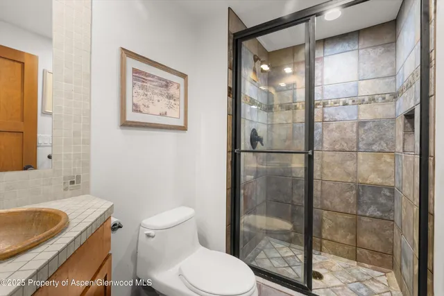 a bathroom with a granite countertop toilet a sink and shower