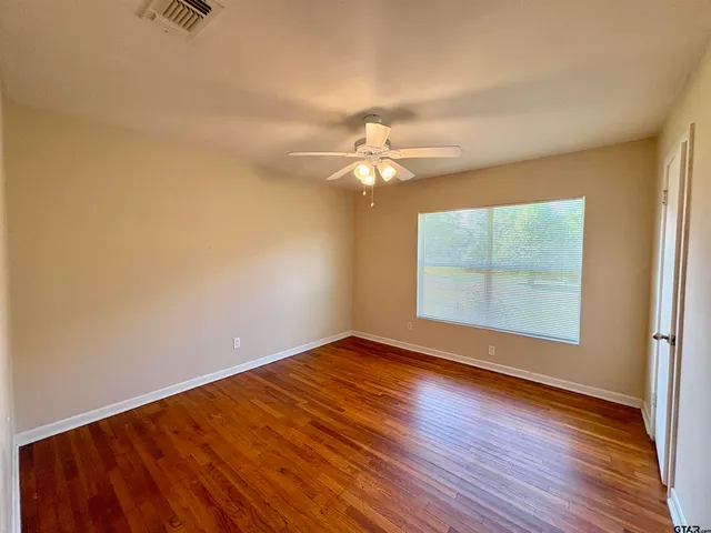 a view of an empty room with wooden floor and a window