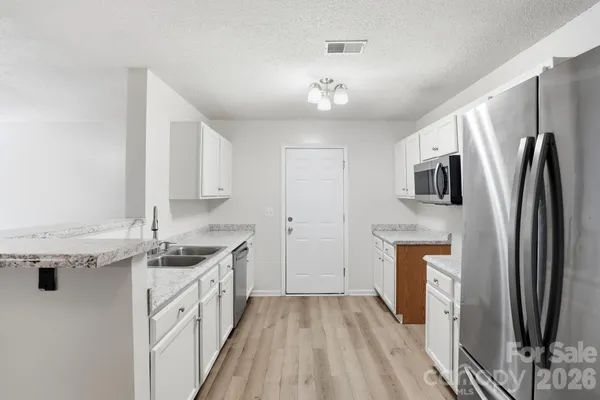 a kitchen with stainless steel appliances granite countertop a sink and dishwasher with white cabinets