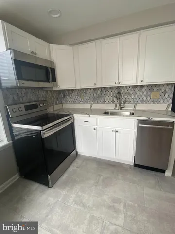 a kitchen with granite countertop white cabinets and stainless steel appliances