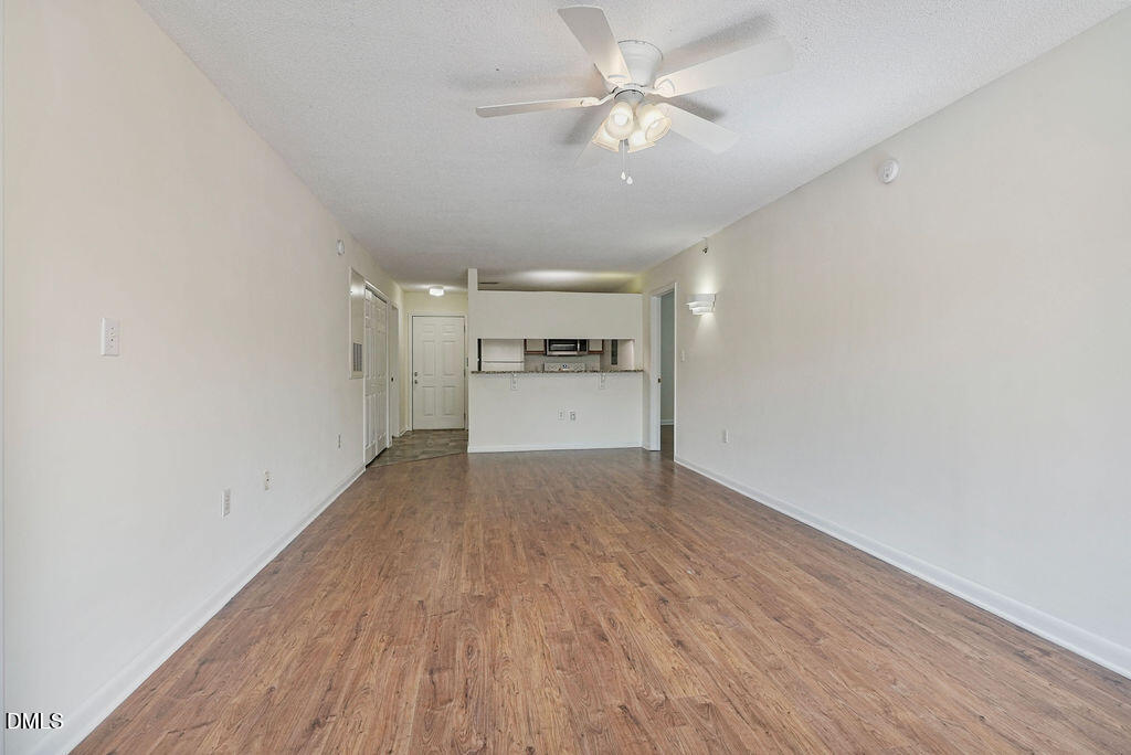1411 Collegiate Circle, Unit 302 Raleigh, NC 27606 - Photo 5 of 43 wooden floor in an empty room with a kitchen