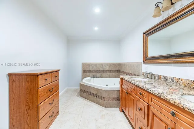 a bathroom with a granite countertop tub sink and mirror